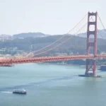 Red and White Fleet ferry boat sailing under the Golden Gate Bridge in San Francisco.