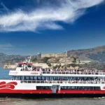 Red and White Fleet sightseeing boat cruising on San Francisco Bay with the Alcatraz Island in the background.