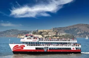 Red and White Fleet sightseeing boat cruising on San Francisco Bay with the Alcatraz Island in the background.