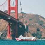 Red and White Fleet sightseeing boat sailing directly under the Golden Gate Bridge in San Francisco.