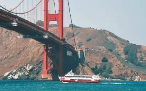 Red and White Fleet sightseeing boat sailing directly under the Golden Gate Bridge in San Francisco.
