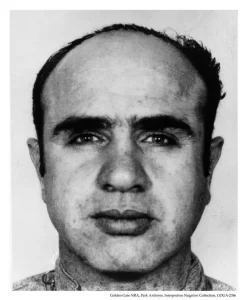 Black and white front-facing and profile mugshot of notorious gangster Al Capone, taken upon his arrival at Alcatraz Federal Penitentiary in 1934.