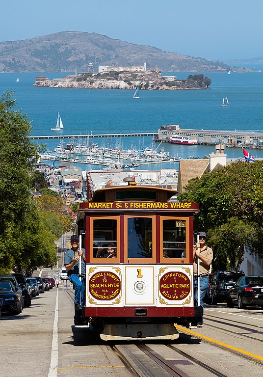 Cable Car climbing Hyde Street with Alcatraz in background - Photo by Thomas Wolf, www.foto-tw.de, CC BY-SA 3.0 <https://creativecommons.org/licenses/by-sa/3.0>, via Wikimedia Commons