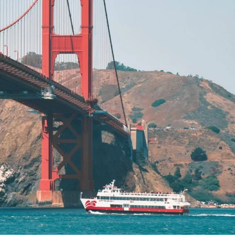 Red and White Fleet bay cruise boat sailing under the Golden Gate Bridge in San Francisco.