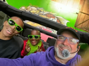 Tour guide Brian and two guests smiling and taking a selfie inside an open-air Jeep during a San Francisco sightseeing tour