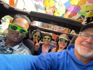 Tour guide Brian and four guests smiling and taking a selfie inside an open-air Jeep at the start of a San Francisco sightseeing tour