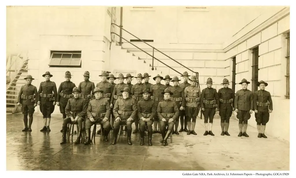 Black and white historical photograph of military medical staff, including nurses in traditional uniforms and officers, standing outside the Alcatraz hospital building in 1918.
