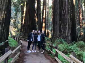Four guests standing among towering giant redwood trees in Muir Woods National Park during a tour from San Francisco