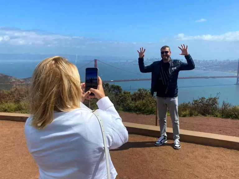 Couple posing for a photo with the Golden Gate Bridge in the background during a San Francisco Jeep sightseeing tour