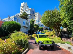 Guests standing in an open-air Jeep while traveling downhill on Lombard Street during a private San Francisco sightseeing tour
