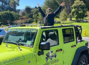 miling guest standing confidently in an open-air Jeep during a San Francisco sightseeing tour near Golden Gate Park