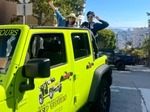 Tour guests posing in an open-air Jeep with the hills of San Francisco in the background during a private sightseeing tour